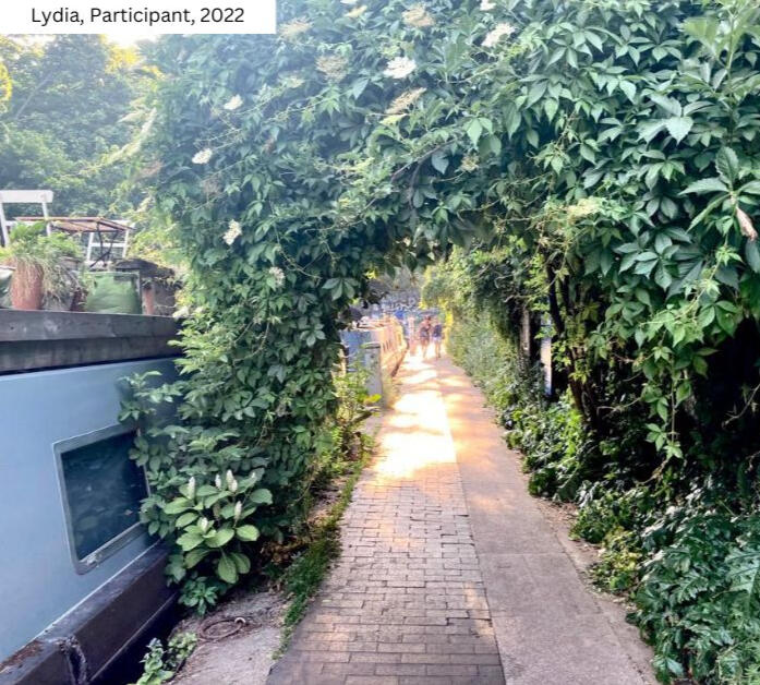 Lush green vine-covered pathway at From Lens to Self workshop. Lydia's 2022 photo captures transformative environment of Gianpietro Pucciariello's London coaching sessions. Nature connection in photography-based personal development.